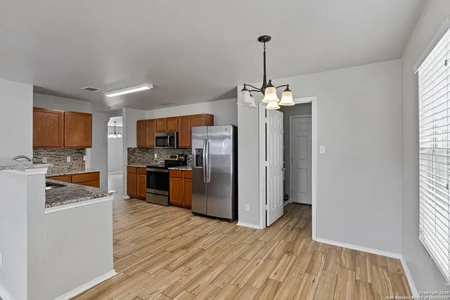 a kitchen with stainless steel appliances granite countertop a refrigerator a oven a sink dishwasher and white cabinets with wooden floor