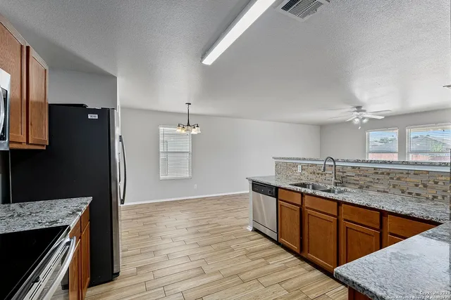a kitchen with stainless steel appliances granite countertop a sink and wooden cabinets
