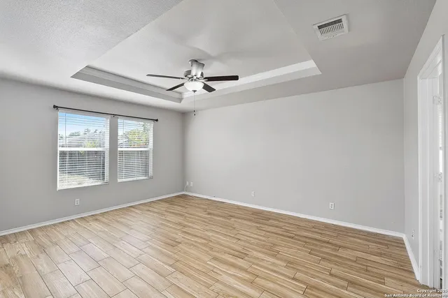 a view of an empty room with a window and wooden floor