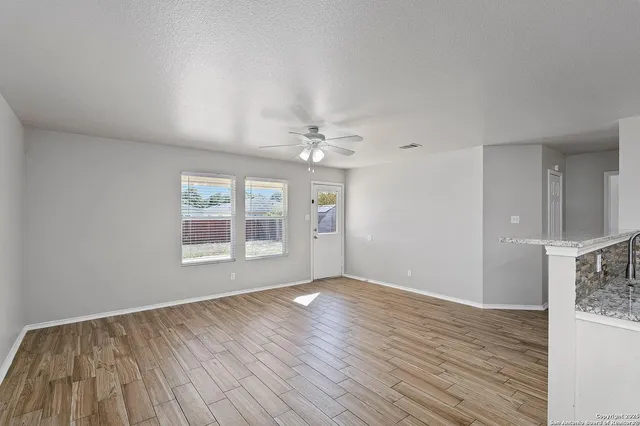 a view of an empty room with wooden floor and a window