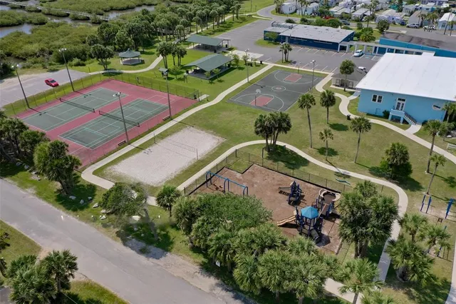 an aerial view of a tennis ground and a cars park side of the road