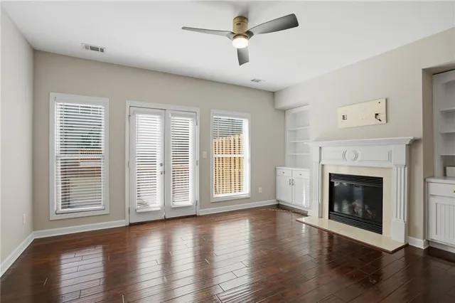 an empty room with wooden floor fireplace and windows