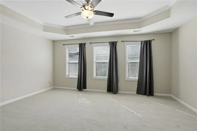 an empty room with chandelier fan and windows