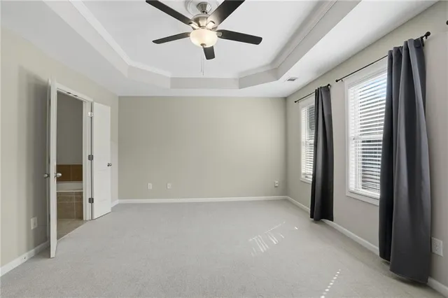 an empty room with chandelier fan and windows