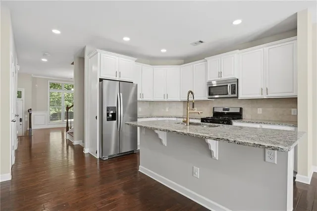 a kitchen with stainless steel appliances granite countertop a refrigerator a stove top oven a sink and dishwasher