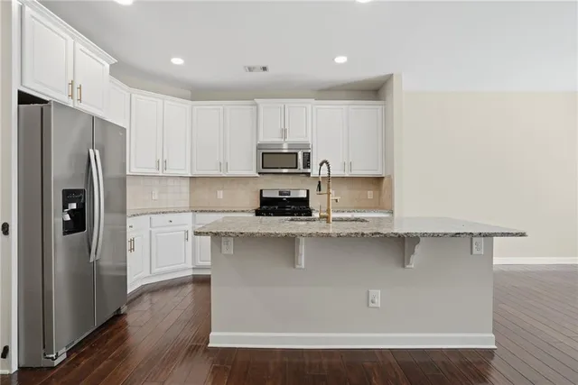 a kitchen with stainless steel appliances a refrigerator a stove top oven a sink and cabinets