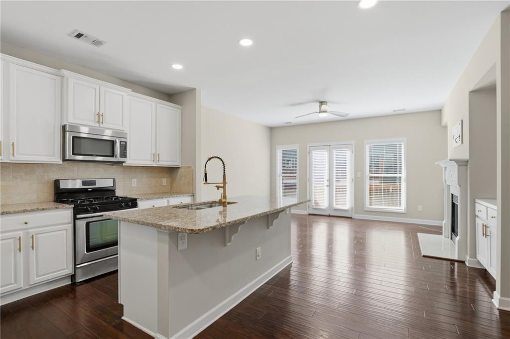 1221 Lavista Road Northeast Atlanta, GA 30324 - Photo 8 of 31 a kitchen with stainless steel appliances granite countertop a stove top oven a sink a refrigerator white cabinets and wooden floor
