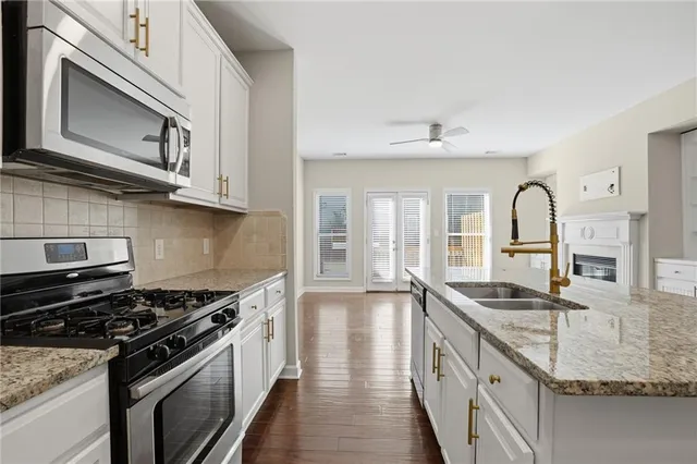 a kitchen with granite countertop stainless steel appliances a sink stove and cabinets