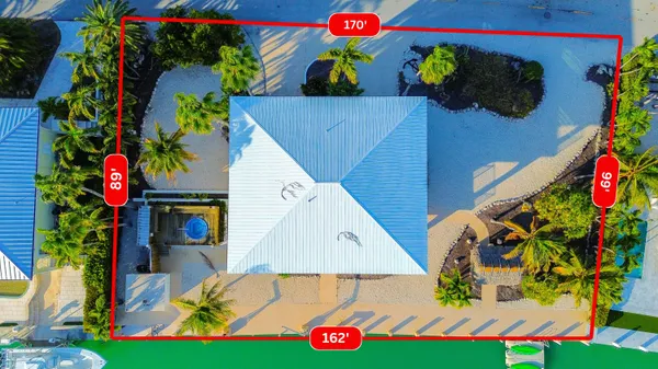 a view of a white house with a yard and table and chairs under an umbrella