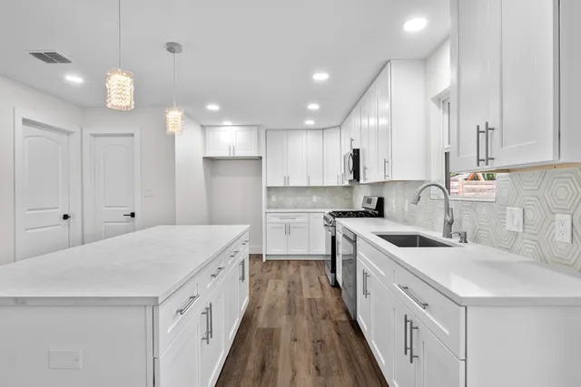 a kitchen with white cabinets sink and stove