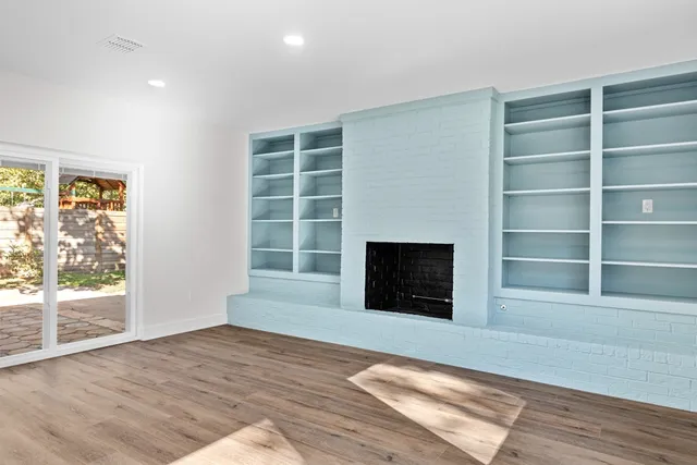 a view of empty room with wooden floor and fireplace