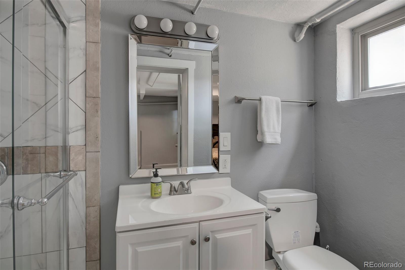 4737 Lowell Boulevard Denver, CO 80211 - Photo 13 of 28 a bathroom with a toilet sink vanity and mirror