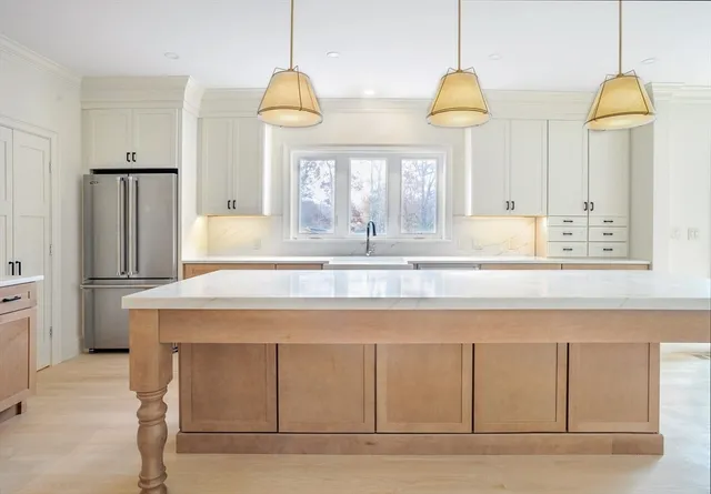 a kitchen with kitchen island granite countertop a stove a sink a background and a chandelier