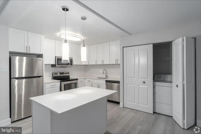 a kitchen with stainless steel appliances a refrigerator a stove a sink and white cabinets