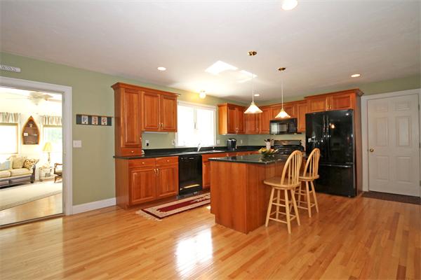 9 Penelope Road Bourne, MA 02532 - Photo 3 of 28 a kitchen with stainless steel appliances granite countertop a refrigerator a stove top oven and a dining table with wooden floor