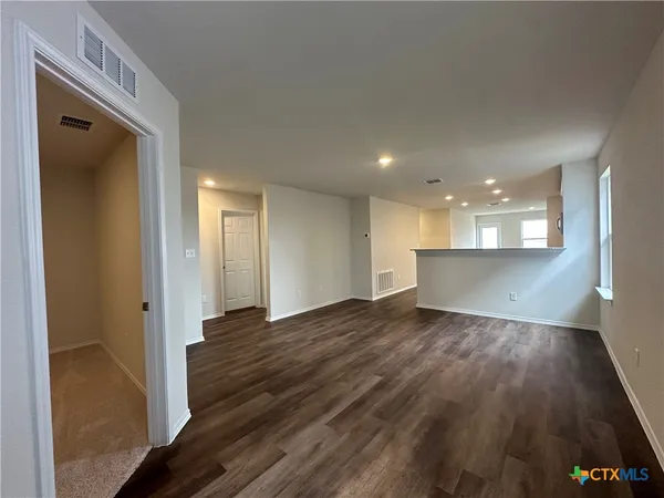 a view of a hallway with wooden floor and a kitchen