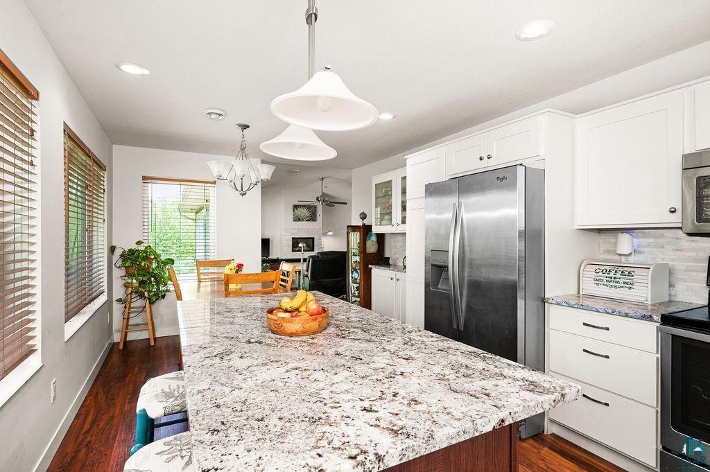 3825 Kenroy Road Hermantown, MN 55811 - Photo 8 of 28 Kitchen featuring a center island, dark wood-type flooring, appliances with stainless steel finishes, decorative light fixtures, and backsplash