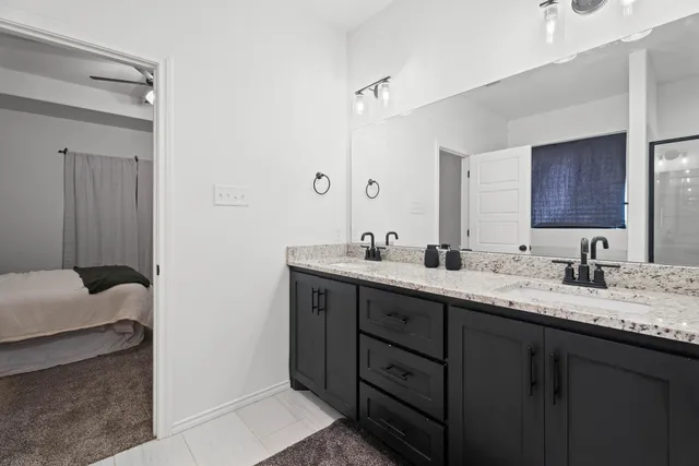 a en suite bathroom with a granite countertop sink and a mirror