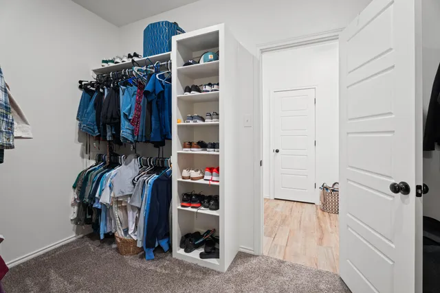 a view of walk in closet with clothes and shoes