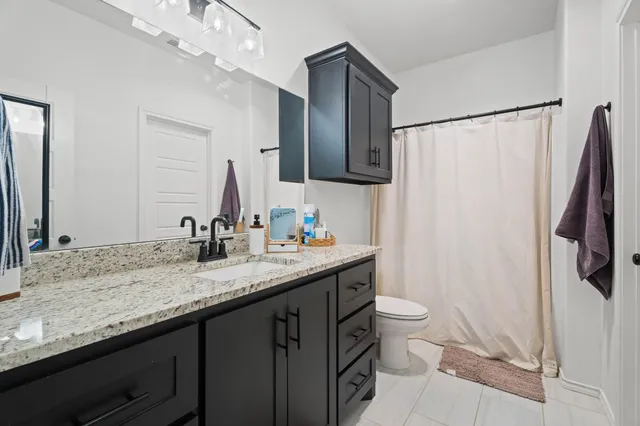 a bathroom with a granite countertop sink toilet and shower