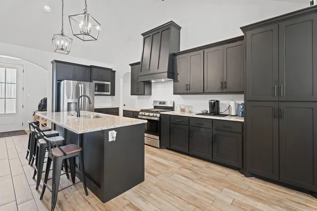 a kitchen with stainless steel appliances granite countertop wooden cabinets a refrigerator a stove a sink and dishwasher