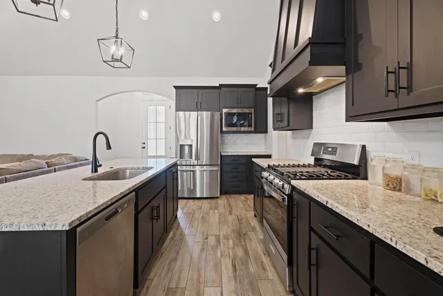 a kitchen with stainless steel appliances granite countertop a sink stove and refrigerator