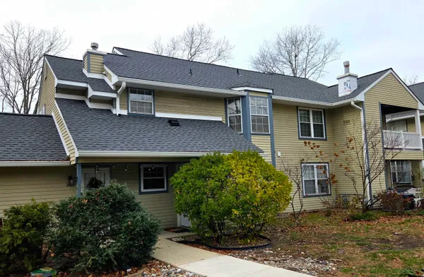 a brick house with a large windows and a yard table and chairs