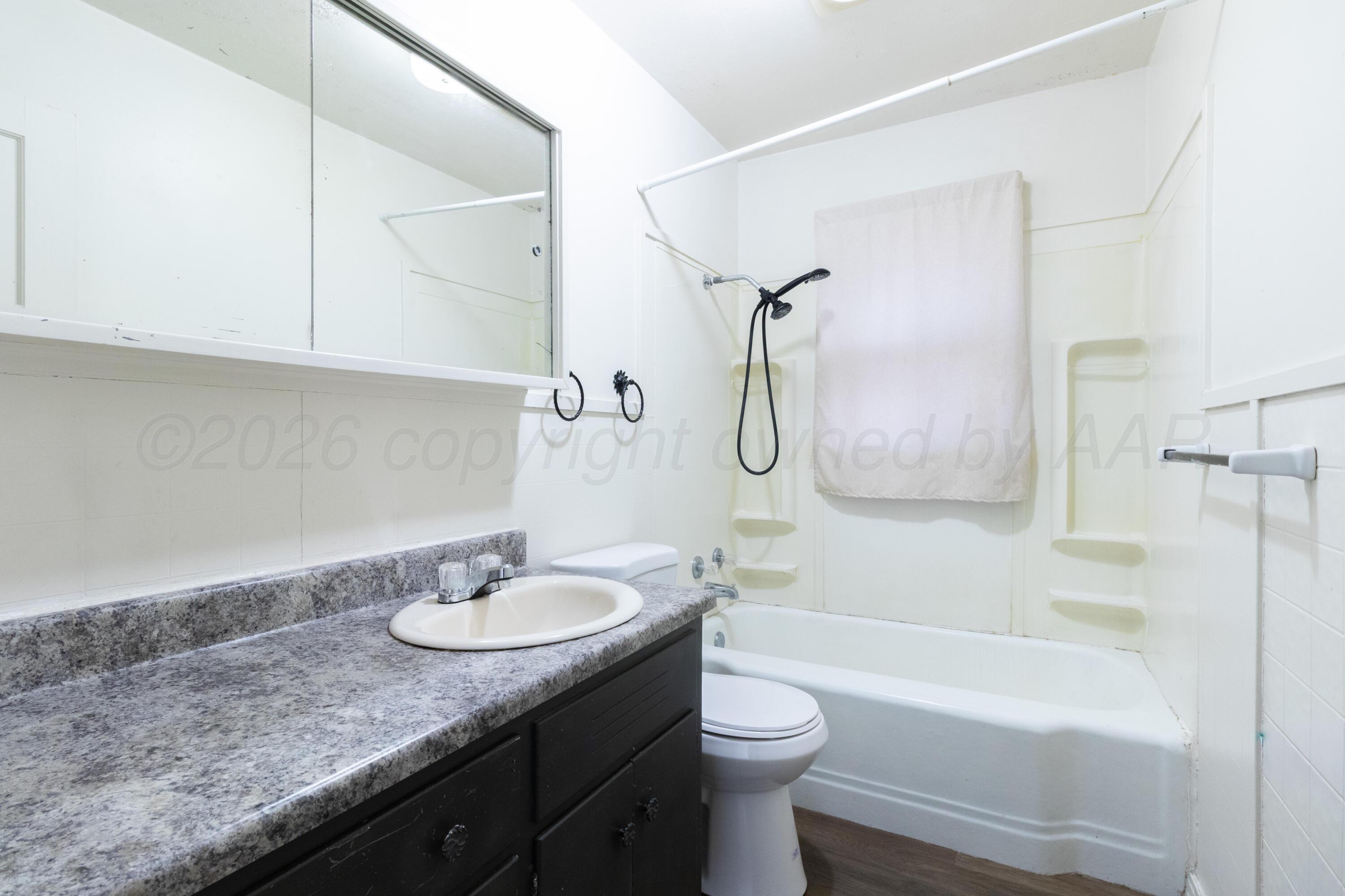 4211 South Travis Street Amarillo, TX 79110 - Photo 16 of 21 a bathroom with a granite countertop sink a toilet and a bathtub