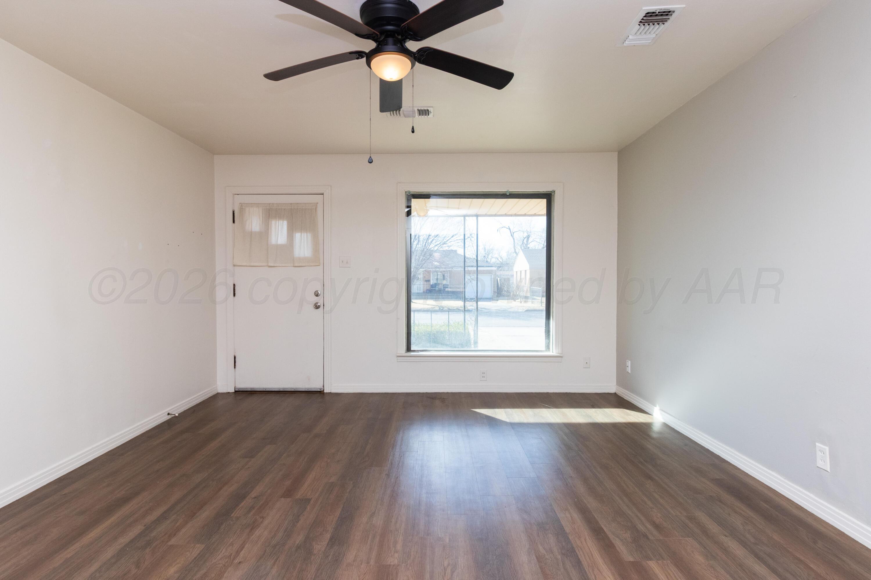 4211 South Travis Street Amarillo, TX 79110 - Photo 5 of 21 an empty room with wooden floor fan and windows