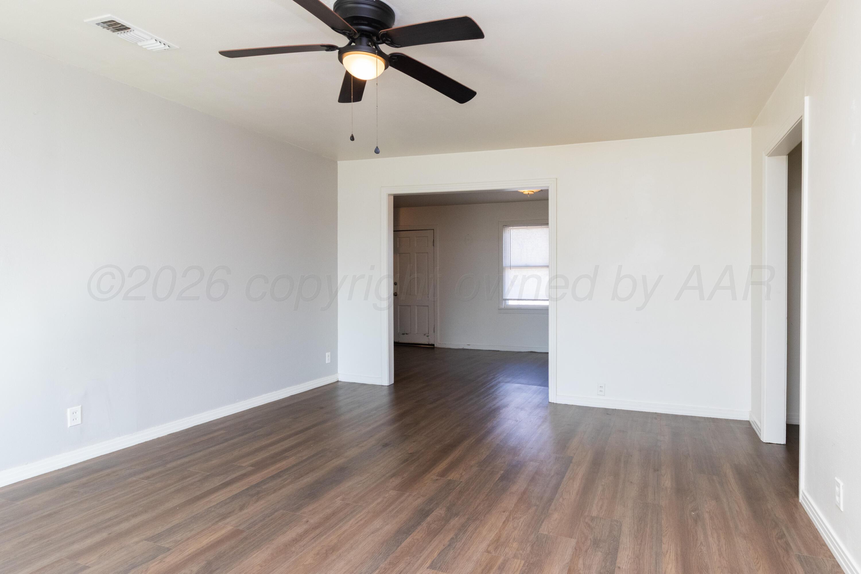 4211 South Travis Street Amarillo, TX 79110 - Photo 6 of 21 a view of an empty room with wooden floor and window