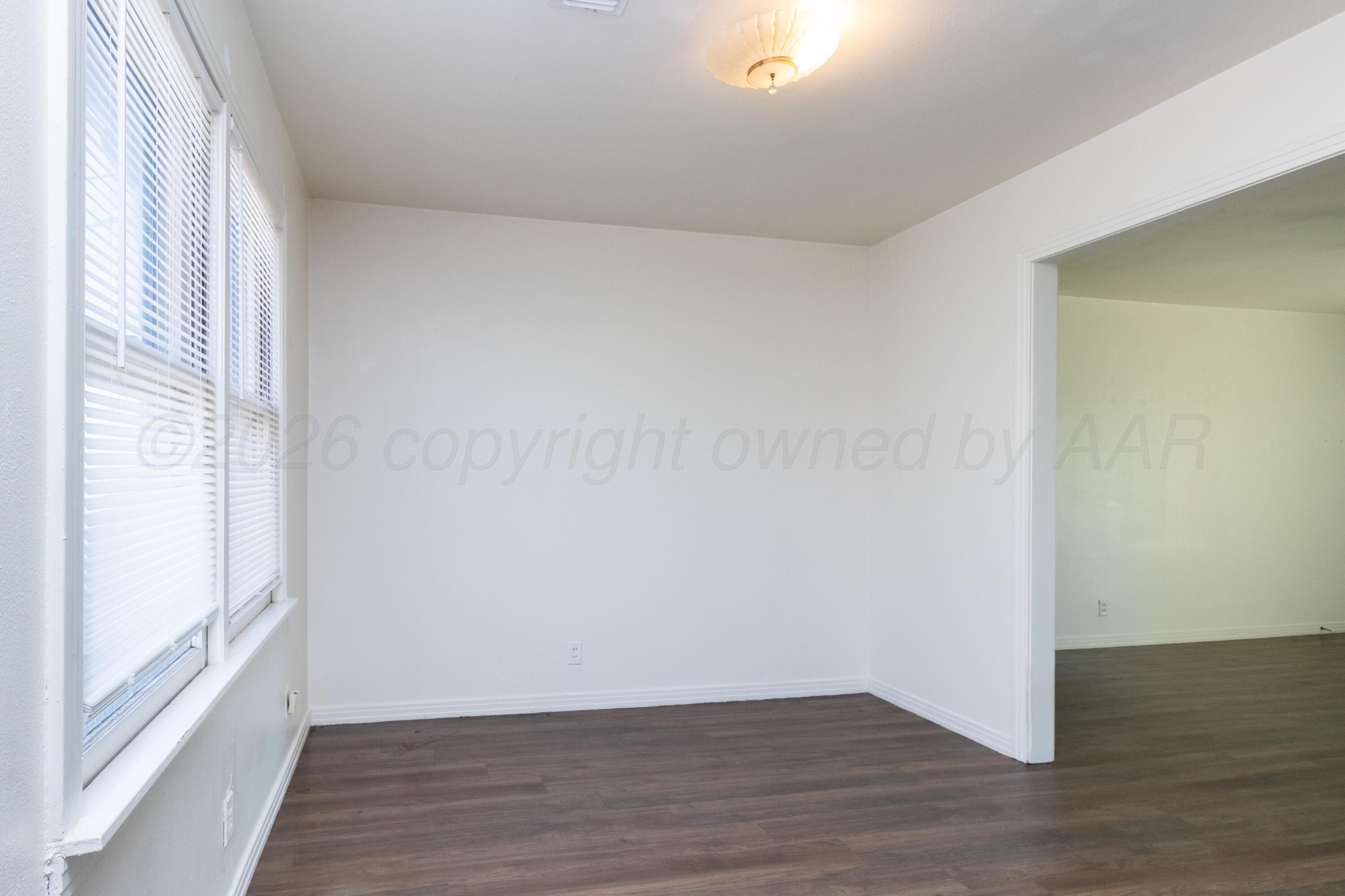 4211 South Travis Street Amarillo, TX 79110 - Photo 7 of 21 a view of an empty room with wooden floor and a window