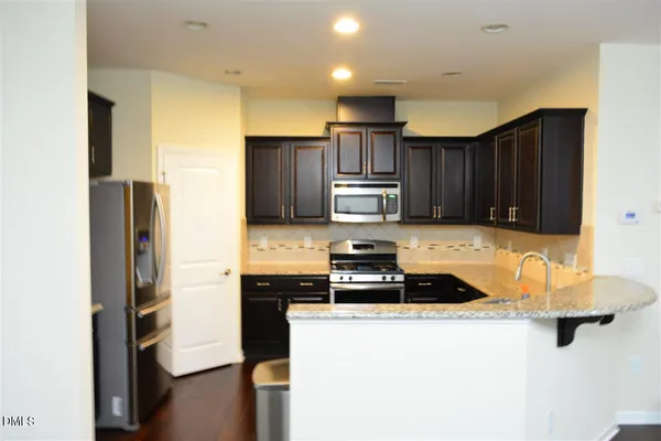 a kitchen with granite countertop a refrigerator stove and sink