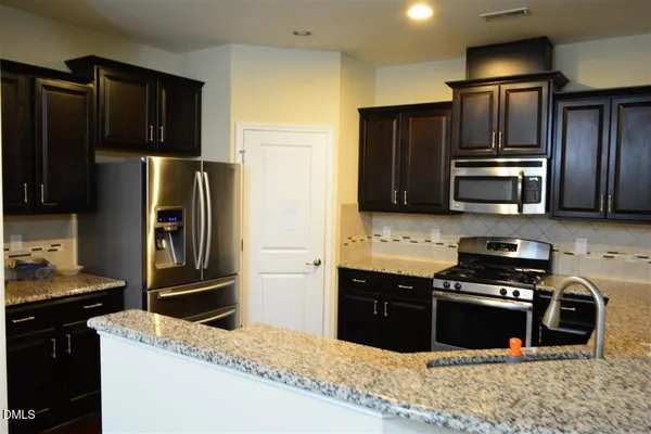 a kitchen with stainless steel appliances granite countertop a refrigerator and a stove