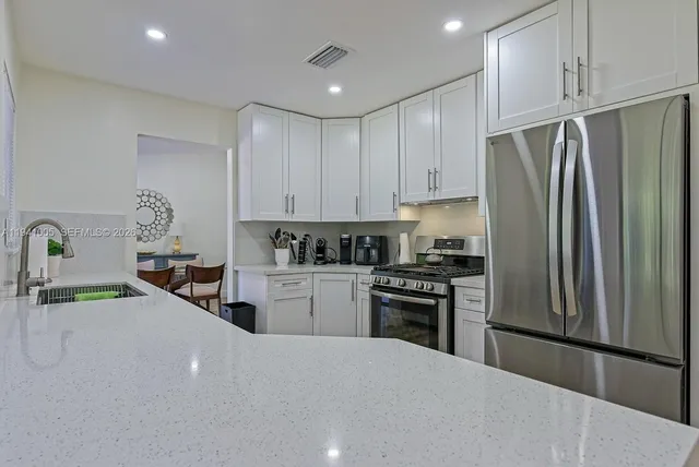 a kitchen with stainless steel appliances granite countertop a refrigerator sink and stove