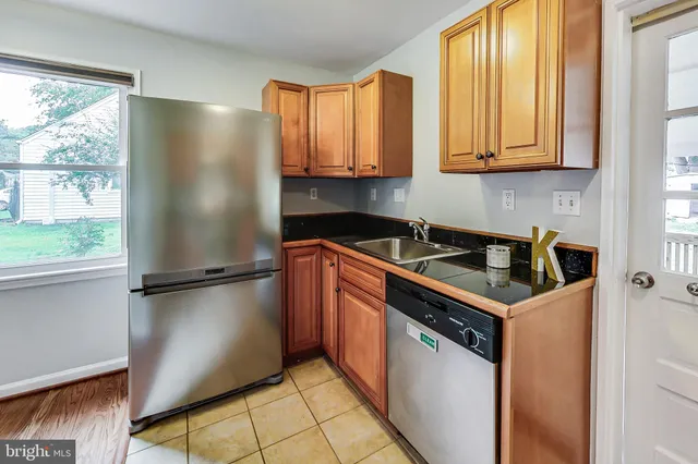 a kitchen with stainless steel appliances granite countertop a refrigerator a sink a stove and white cabinets with wooden floor