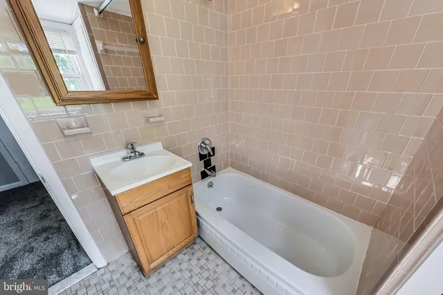 a bathroom with a tub sink and mirror