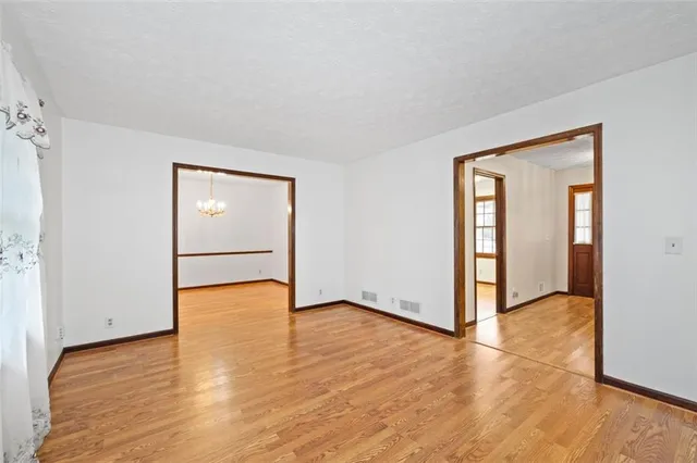 an empty room with chandelier fan and windows
