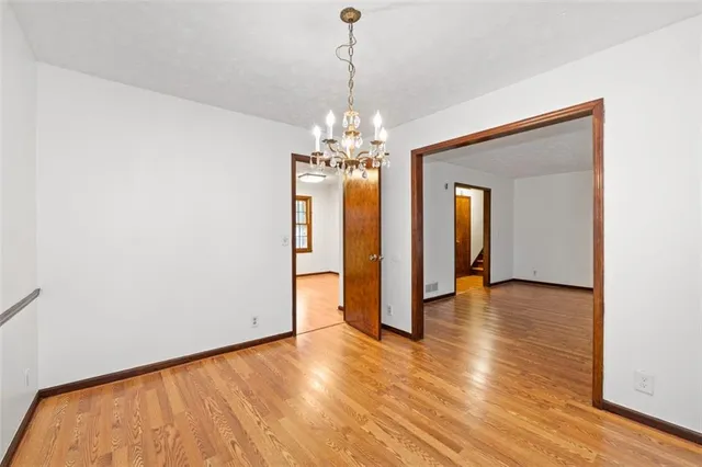 a view of empty room with wooden floor and ceiling fan