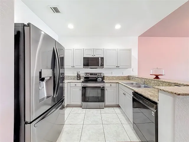 a kitchen with stainless steel appliances granite countertop a refrigerator and a stove top oven