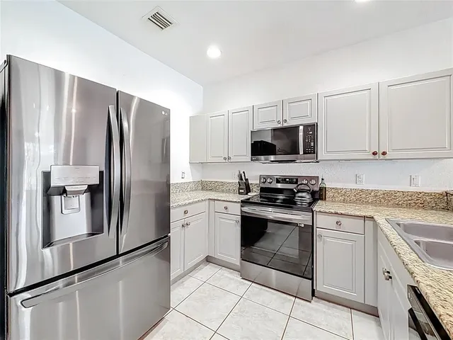 a kitchen with stainless steel appliances granite countertop a refrigerator sink and stove