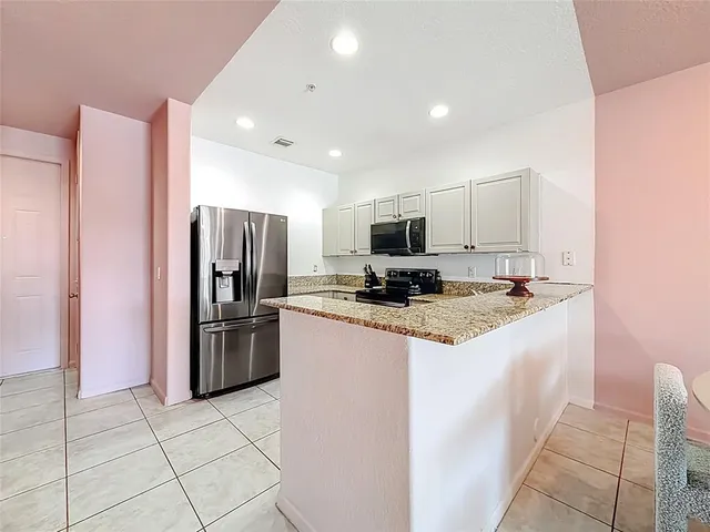 a kitchen with kitchen island granite countertop a refrigerator and a stove top oven
