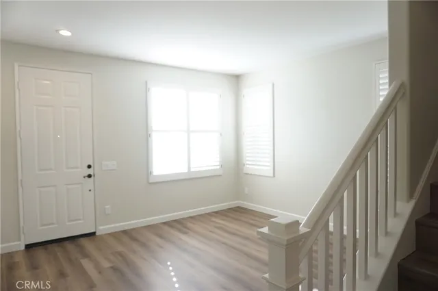 a view of an empty room with wooden floor and stairs