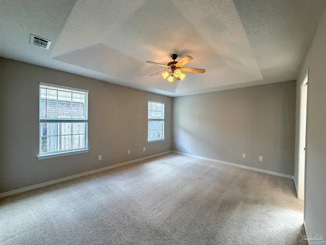 an empty room with windows and chandelier fan