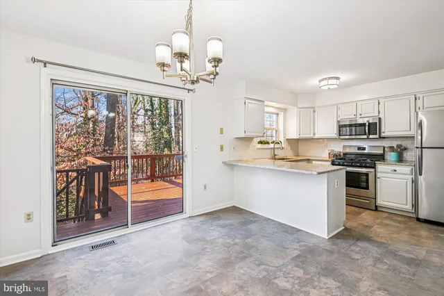 a kitchen with stainless steel appliances granite countertop a refrigerator a sink dishwasher a stove and a dining table with wooden floor