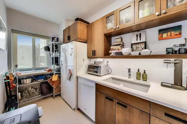 a kitchen with stainless steel appliances a refrigerator a sink and wooden cabinets