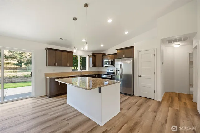 a kitchen with stainless steel appliances granite countertop a refrigerator a sink dishwasher a stove and white countertops with wooden floor