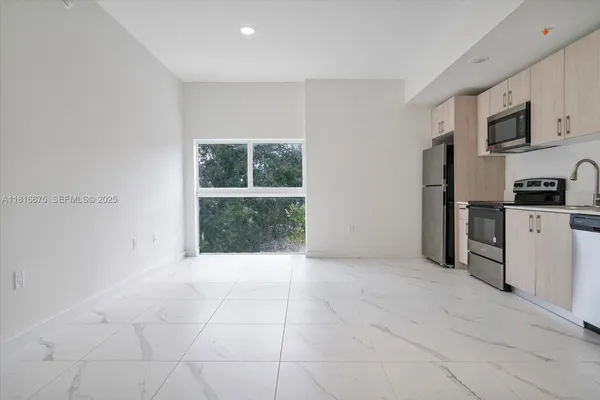 a view of kitchen with granite countertop cabinets and refrigerator