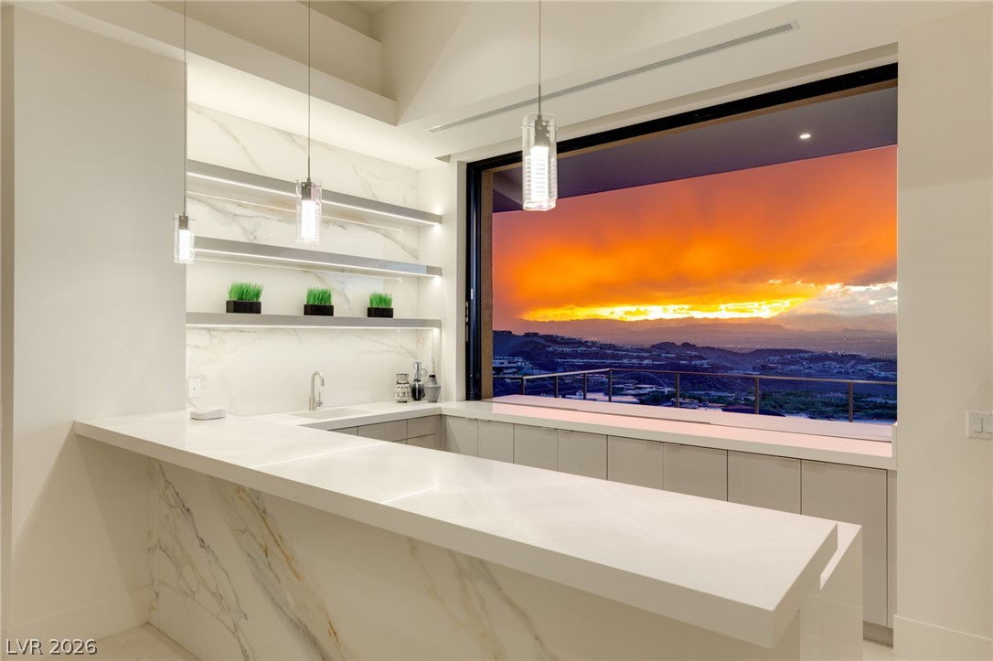 677 Overlook Rim Drive Henderson, NV 89012 - Photo 8 of 97 A wide window frames dramatic mountain sunset views from behind the sleek stone bar.