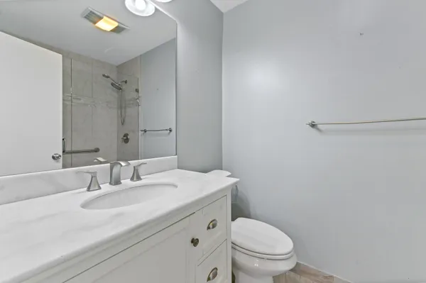 a bathroom with a granite countertop sink a toilet and a mirror
