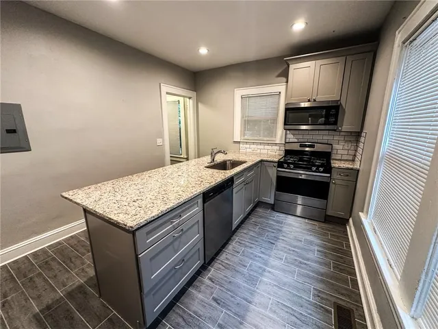 a living room with stainless steel appliances granite countertop furniture wooden floor and a window